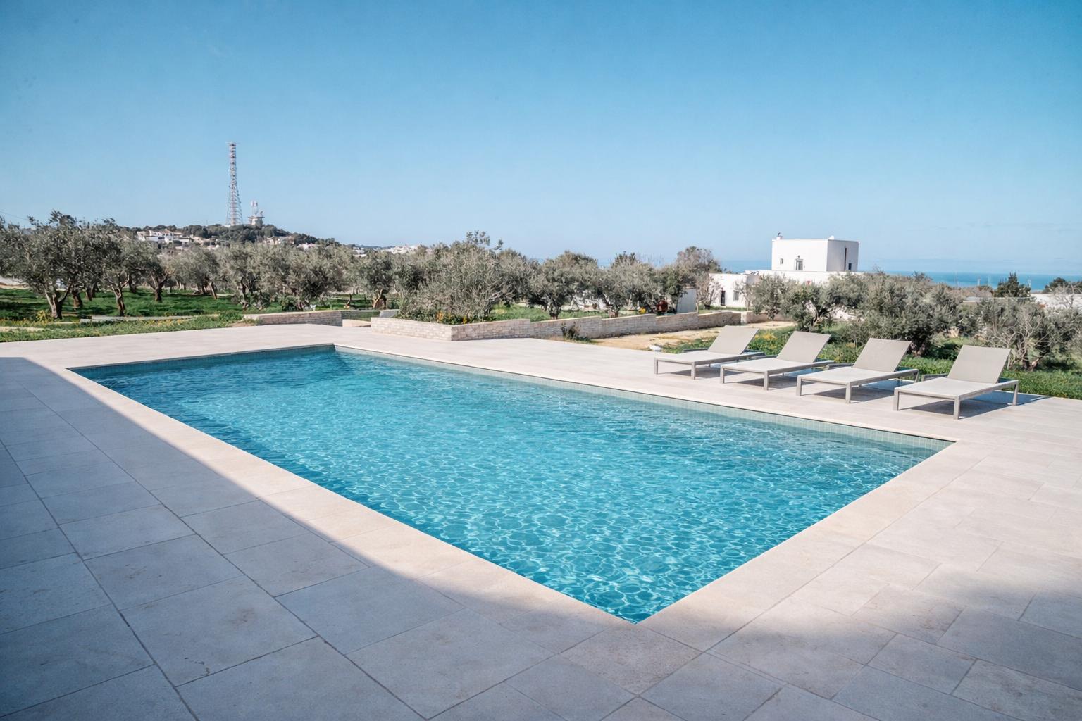 Pool mit Liegen und Blick auf Olivenhaine und das Meer.