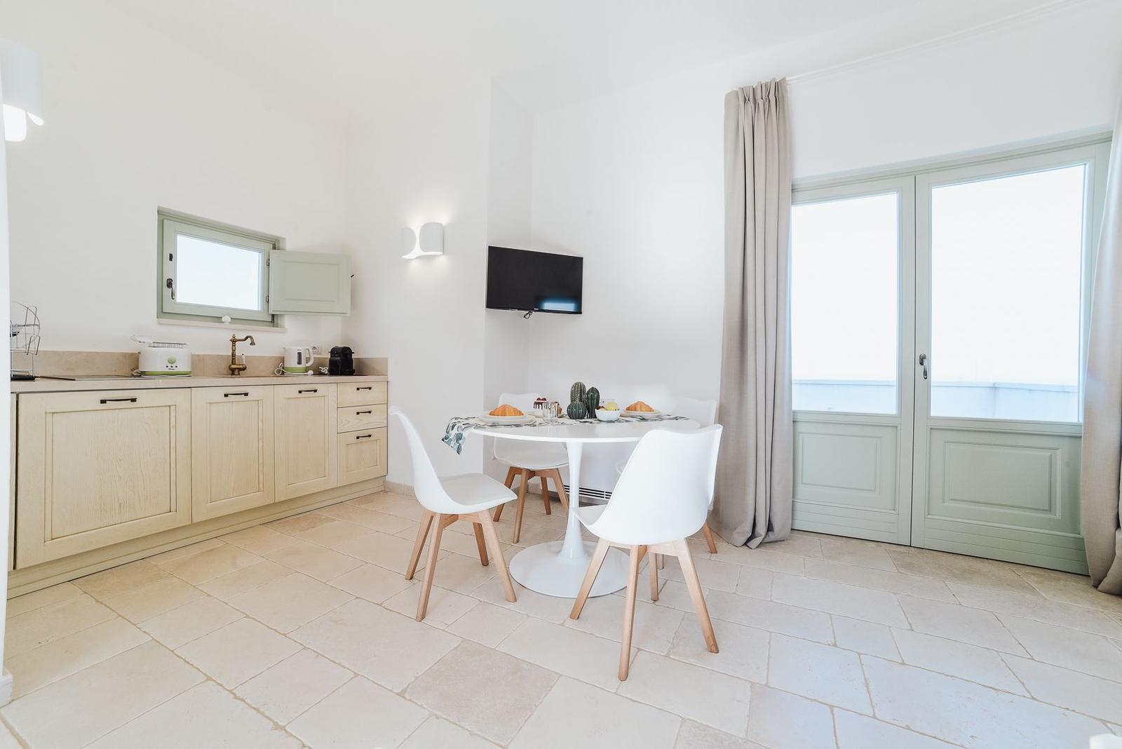 Küche mit Esstisch, TV und Balkontür.