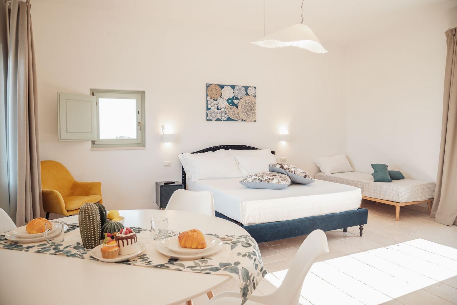 Schlafzimmer mit Bett, Sitzbank und Esstisch mit Frühstück.