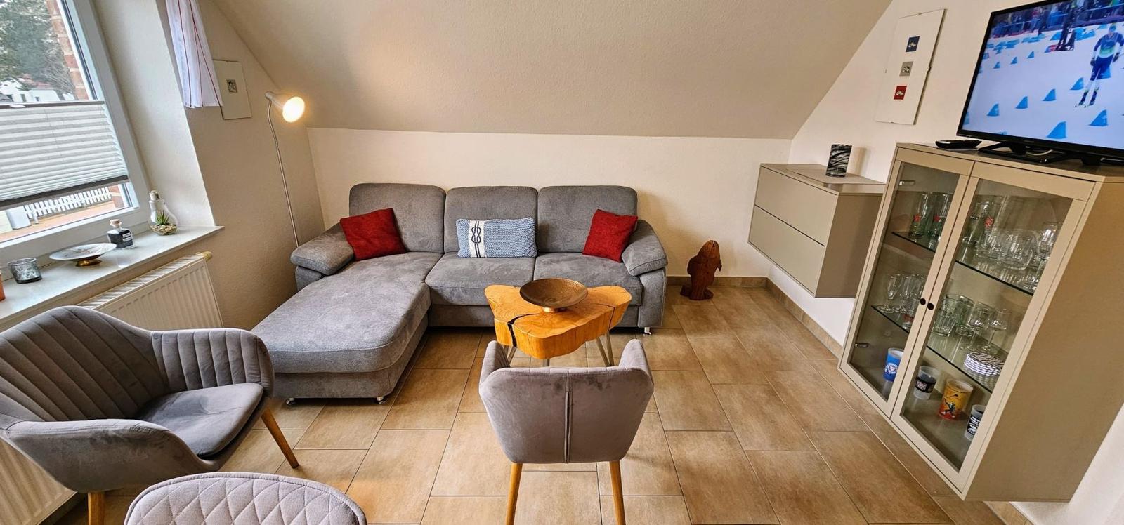 Wohnzimmer mit grauem Sofa, Holztisch und Fernseher