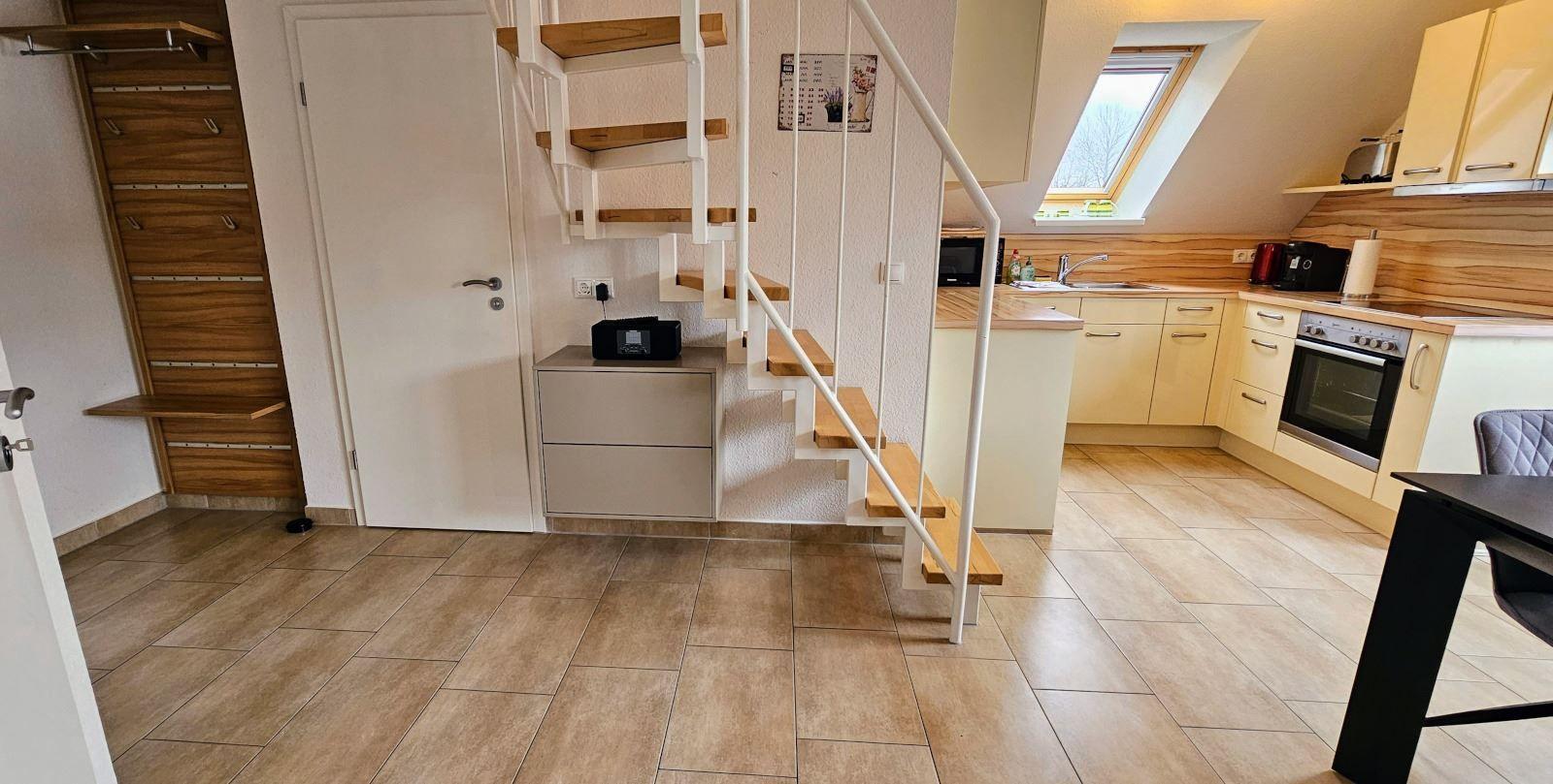 Küche mit Holzoptik, Dachfenster und Treppe zur oberen Etage.