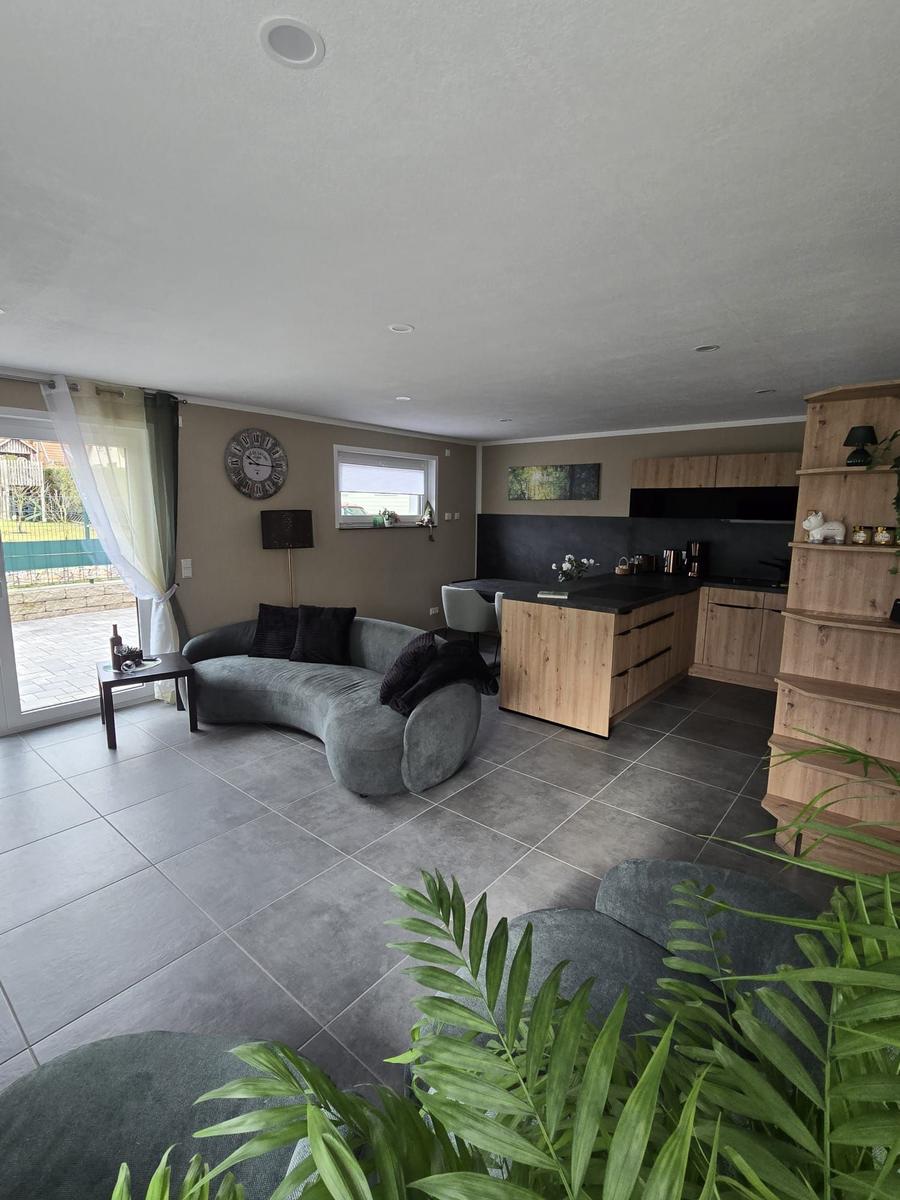 Wohn- und Küchenbereich mit Holzmöbeln und großem Fenster.