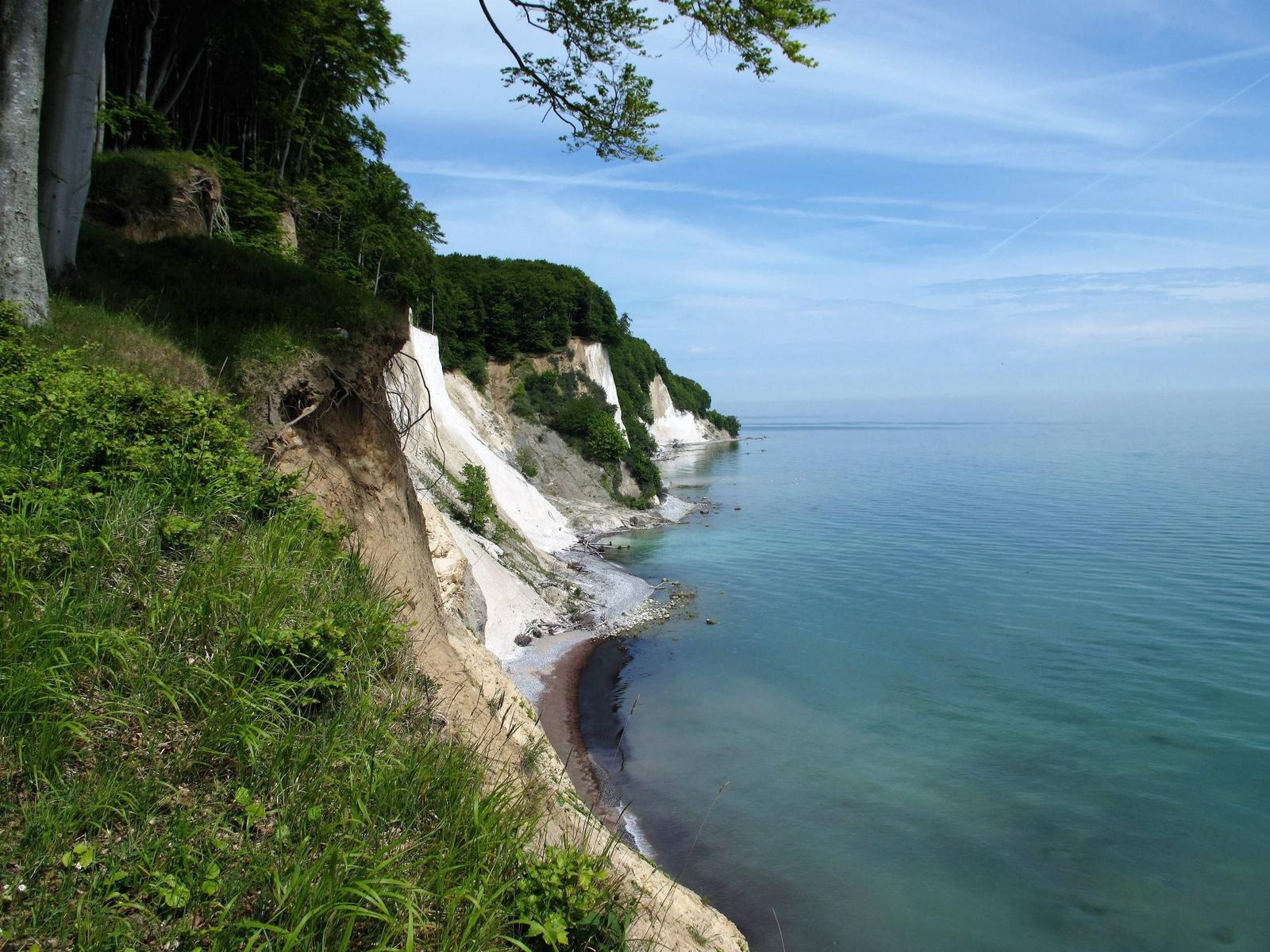 Steilküste mit grüner Vegetation und blauem Meer unter klarem Himmel.