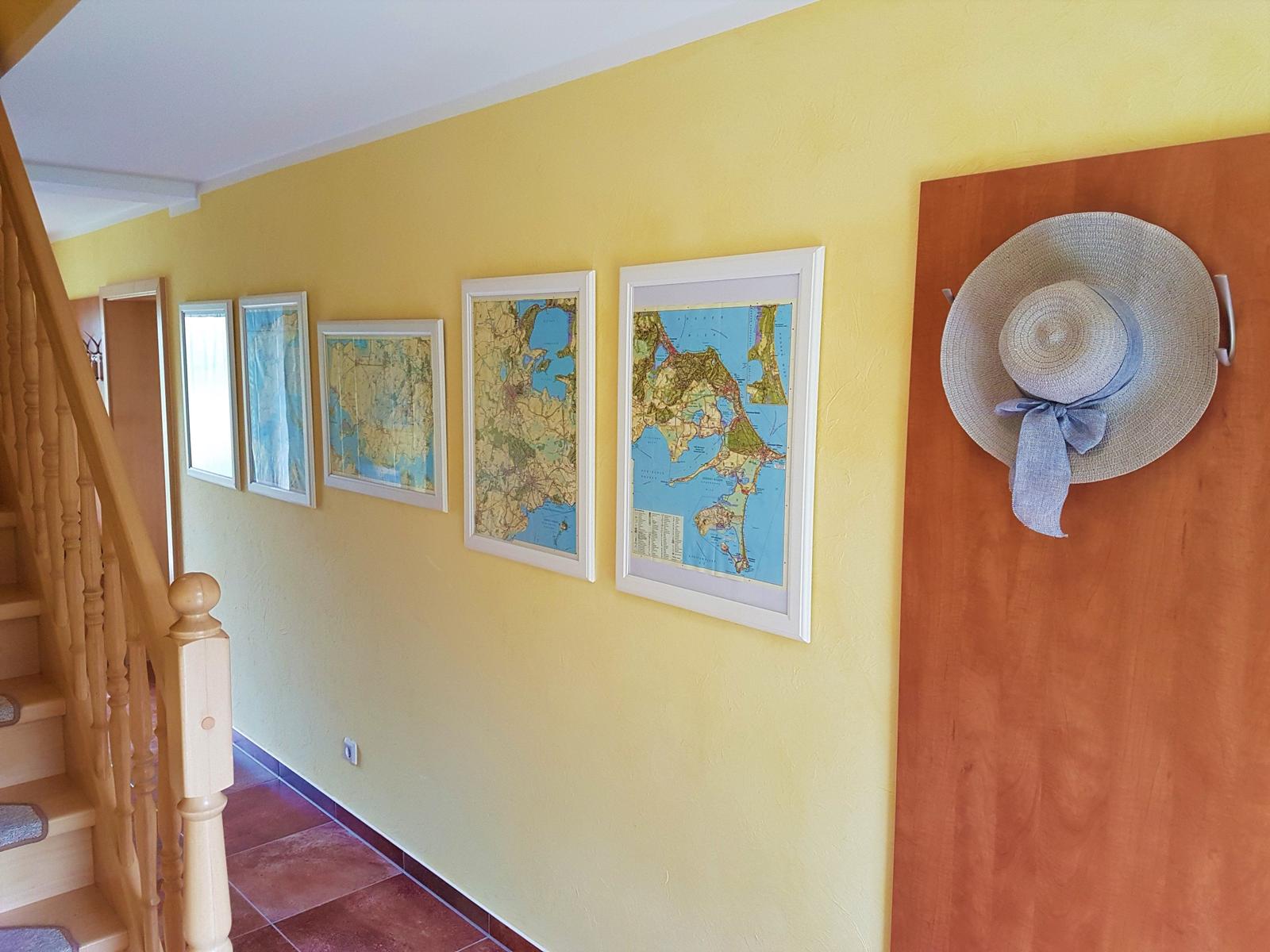 Flur mit gelber Wand, Karten und Strohhut an Tür
