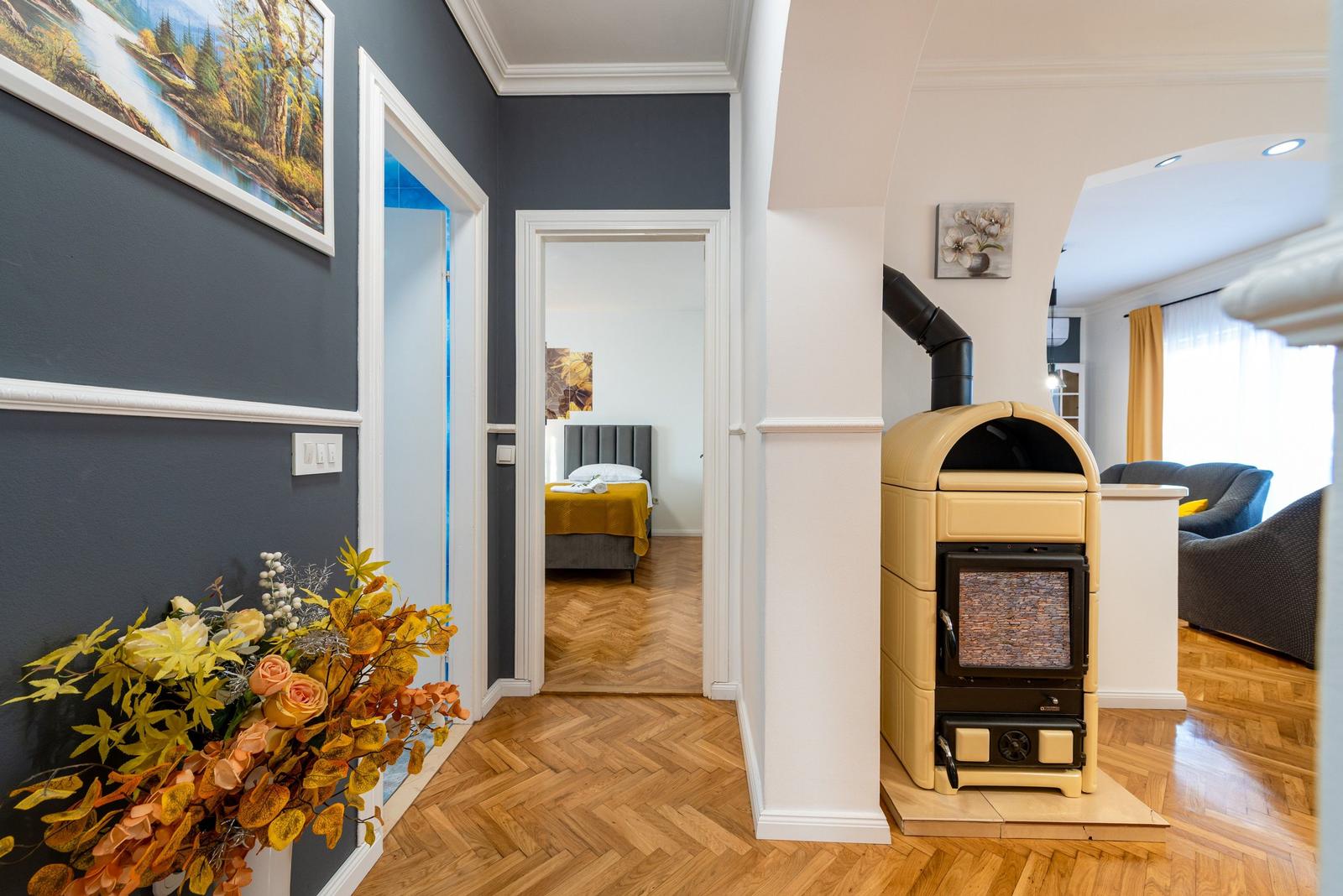 Haus mit Holzfußboden, Kaminofen und Blick in Schlafzimmer und Wohnbereich.