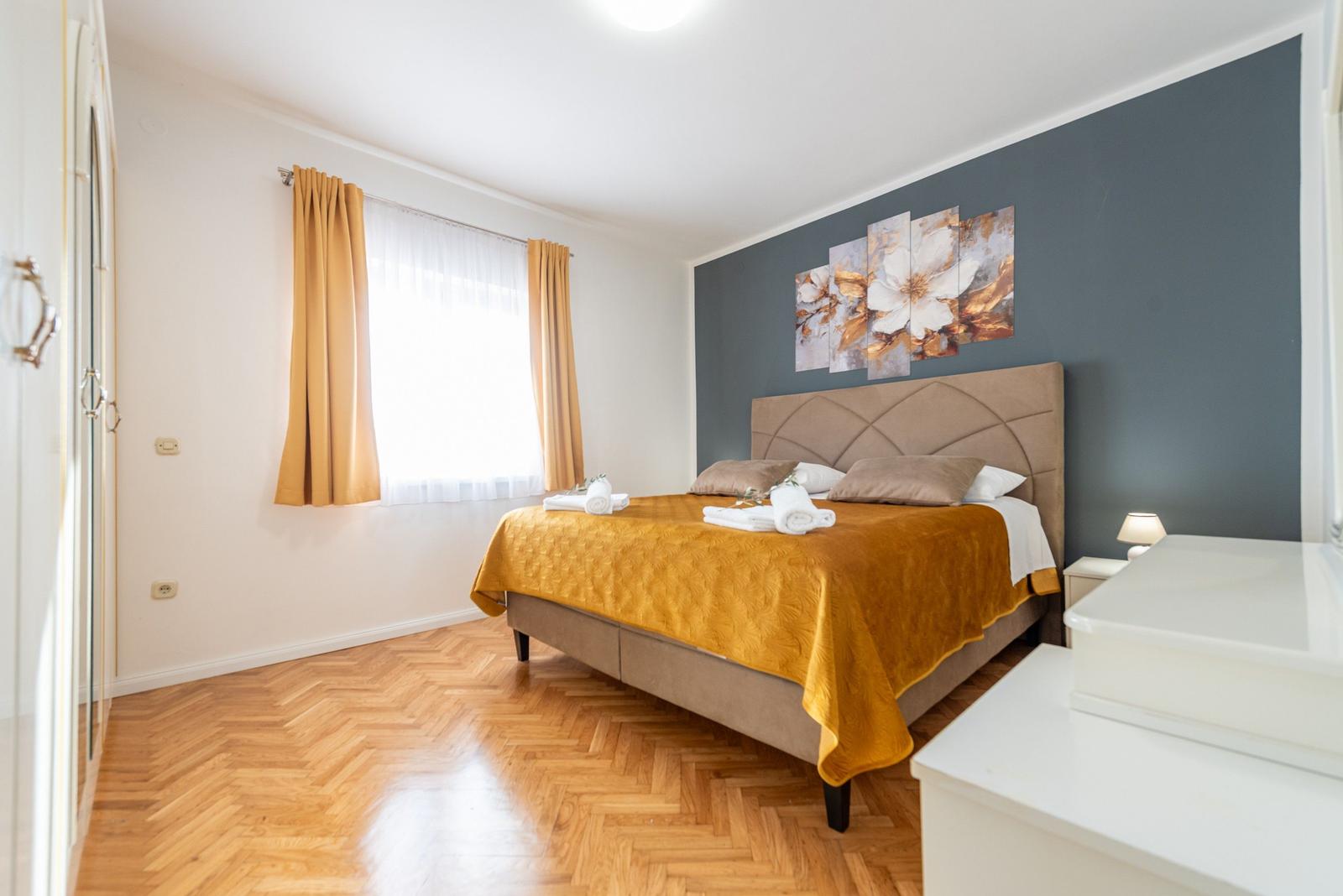 Schlafzimmer mit Bett, Wandbild und Holzboden