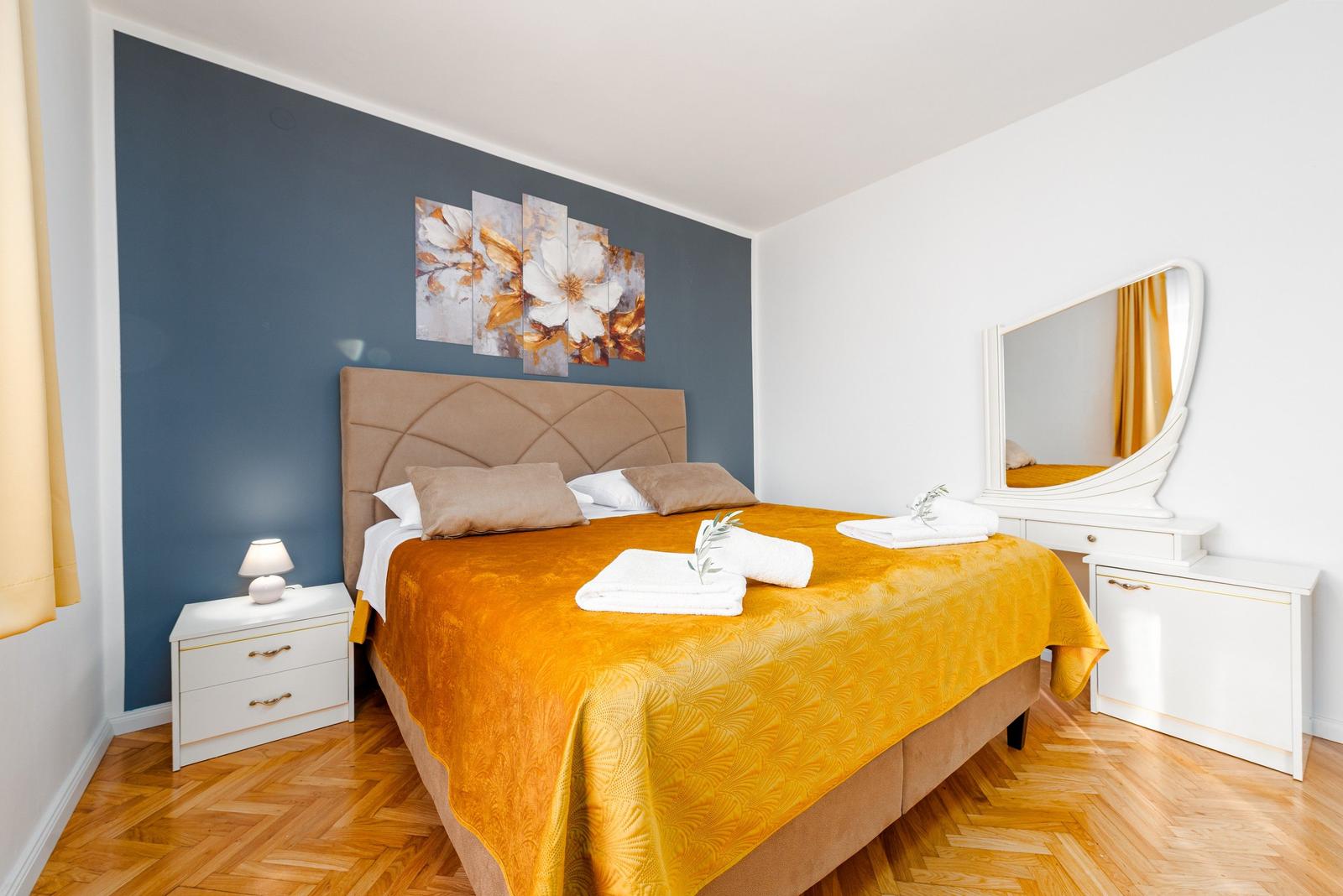 Schlafzimmer mit Bett, Schminktisch und Wandbild.