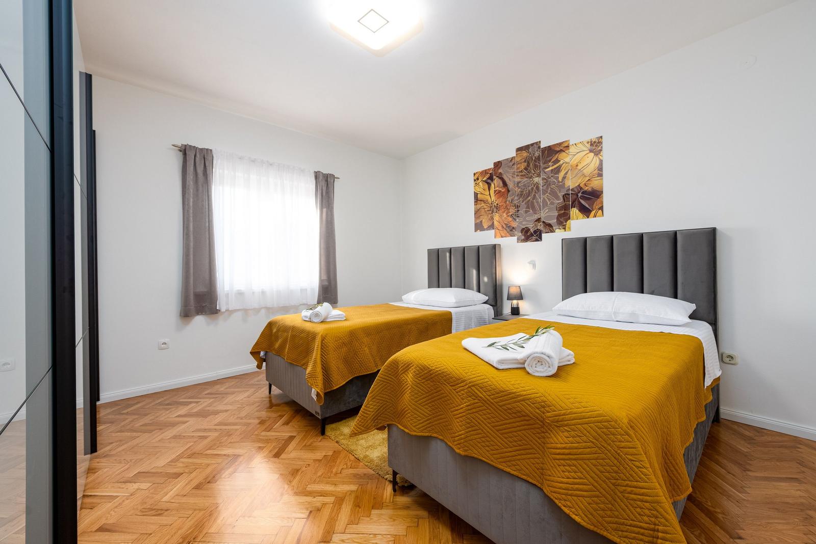 Zwei Betten mit gelben Decken, Holzboden und Wandbild