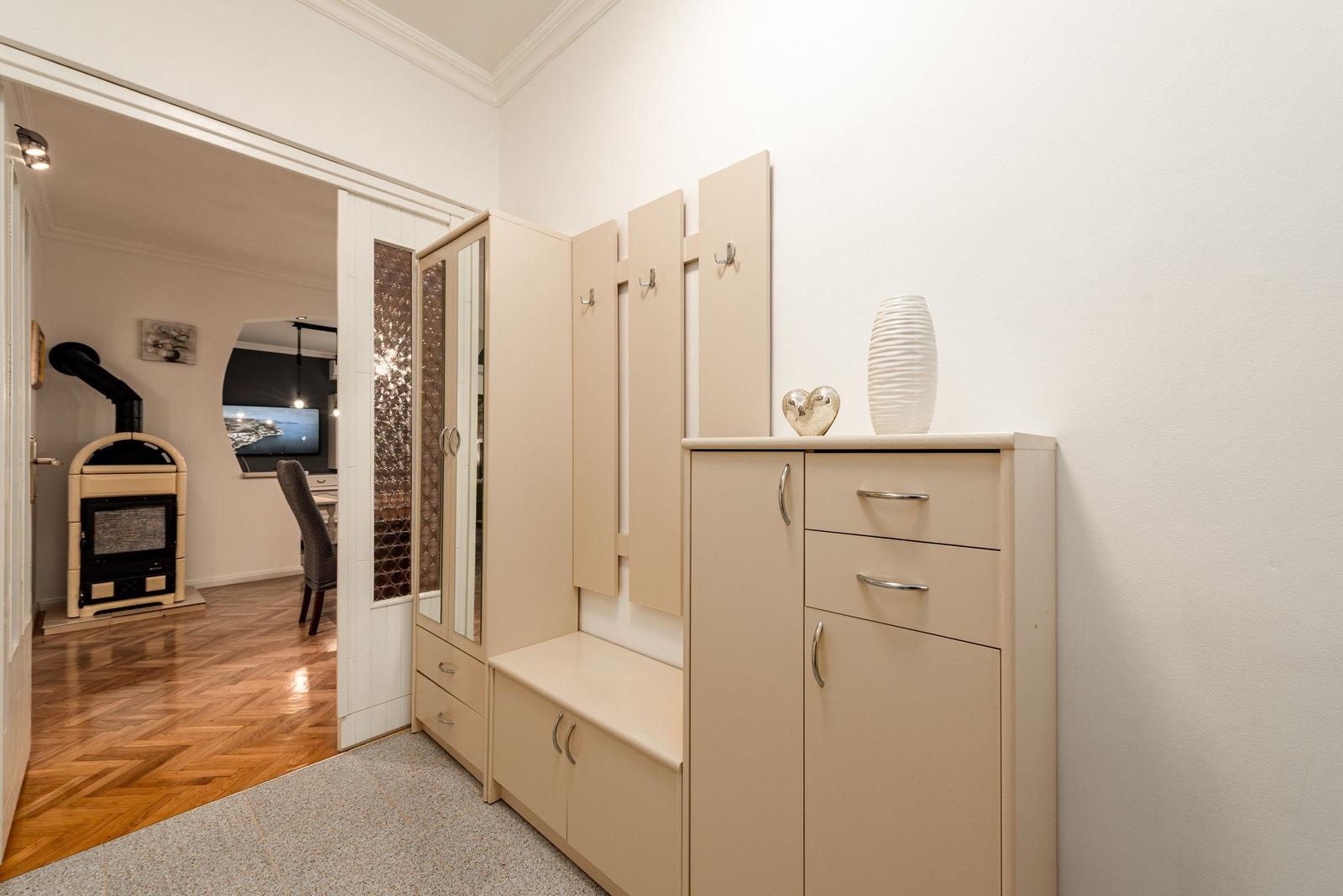 Eingangsbereich mit Garderobe und Schuhschrank. Durchgang in Wohnbereich mit Kamin und Fernseher.