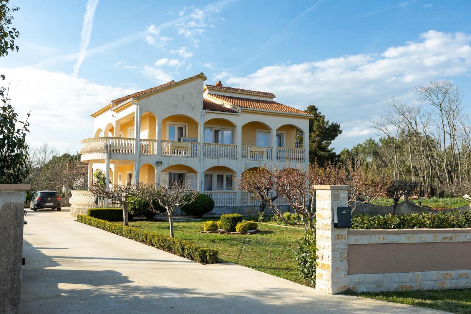 Zweistöckiges Haus mit Balkonen und gepflegtem Garten.