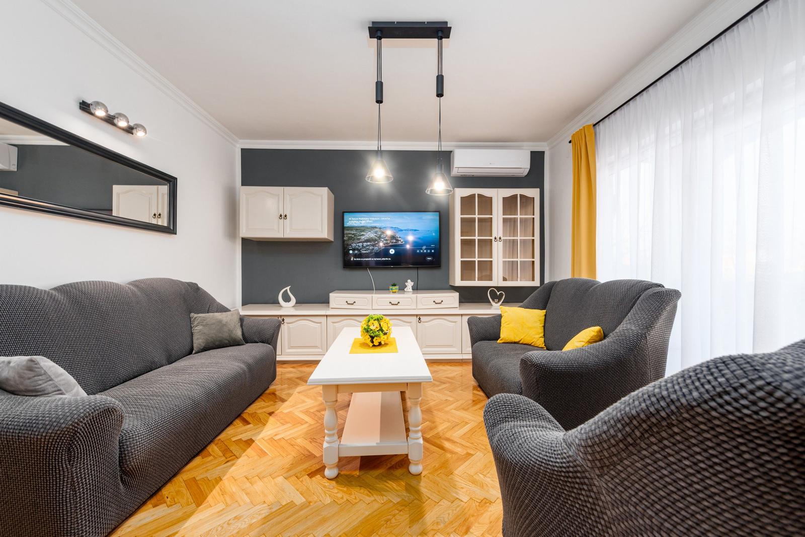 Wohnzimmer mit grauen Sofas, weißem Tisch und Holzboden