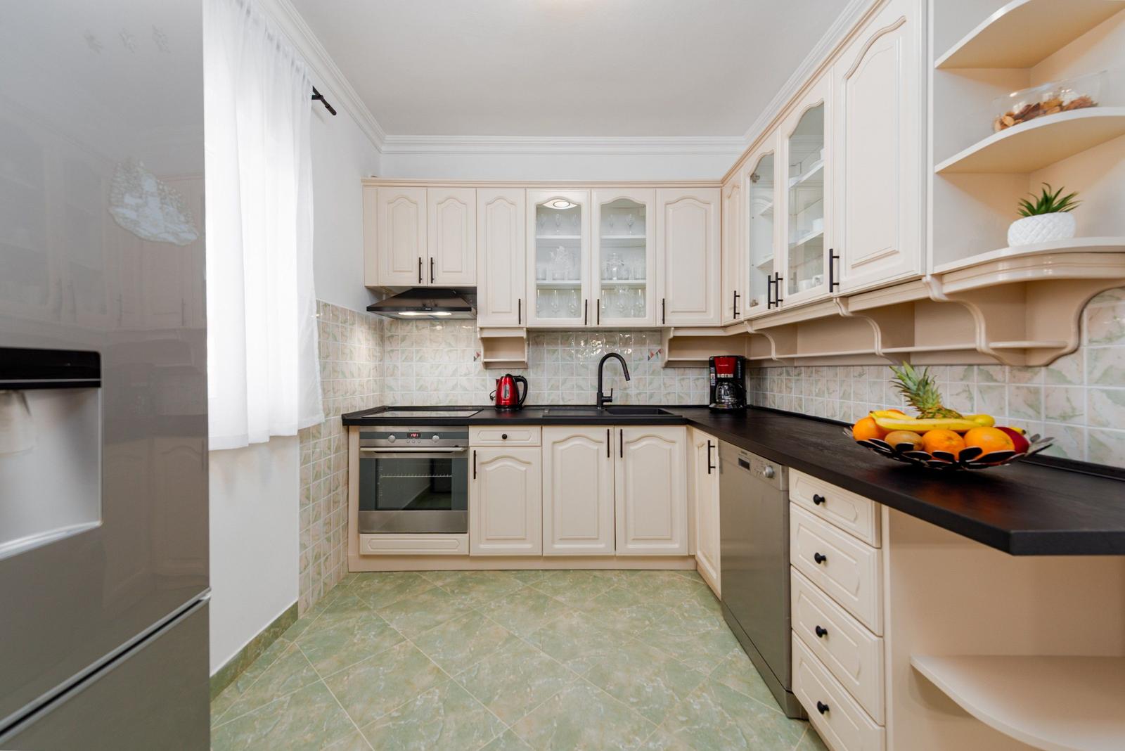 Küche mit weißen Schränken, dunklem Arbeitsplatz und Küchenzeile