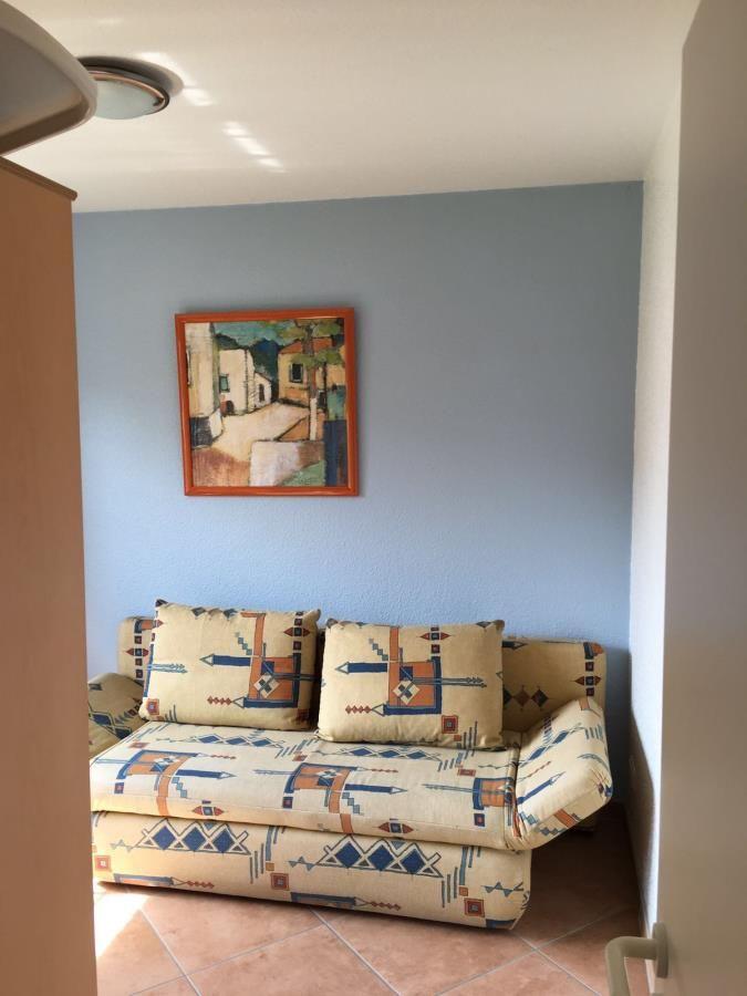 Ein Sofa mit gemustertem Stoff steht vor einer blauen Wand. Darüber hängt ein Bild in einem Holzrahmen.