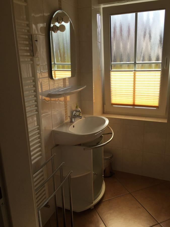 Bad mit Waschbecken, Spiegel und Fenster mit Jalousie.