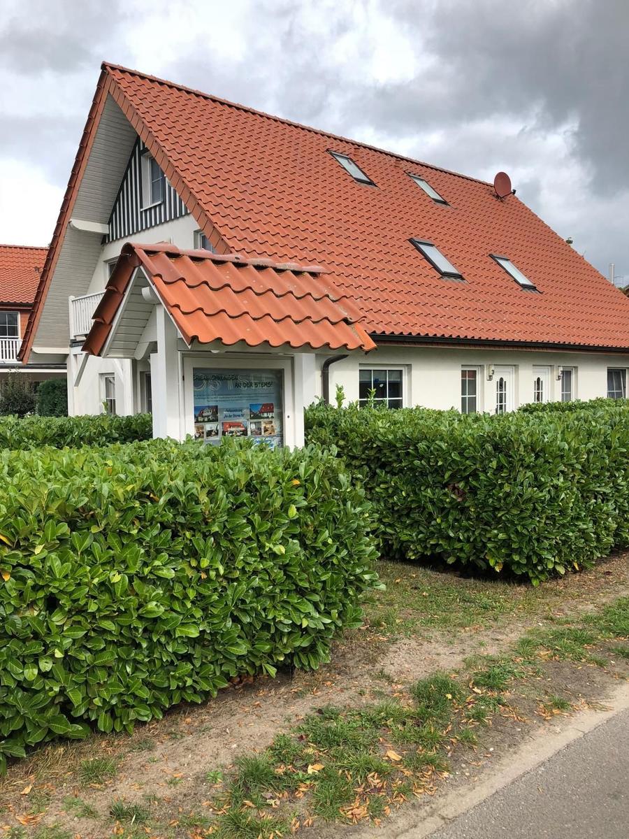 Wohnhaus mit rotem Ziegeldach und grünen Hecken vorne
