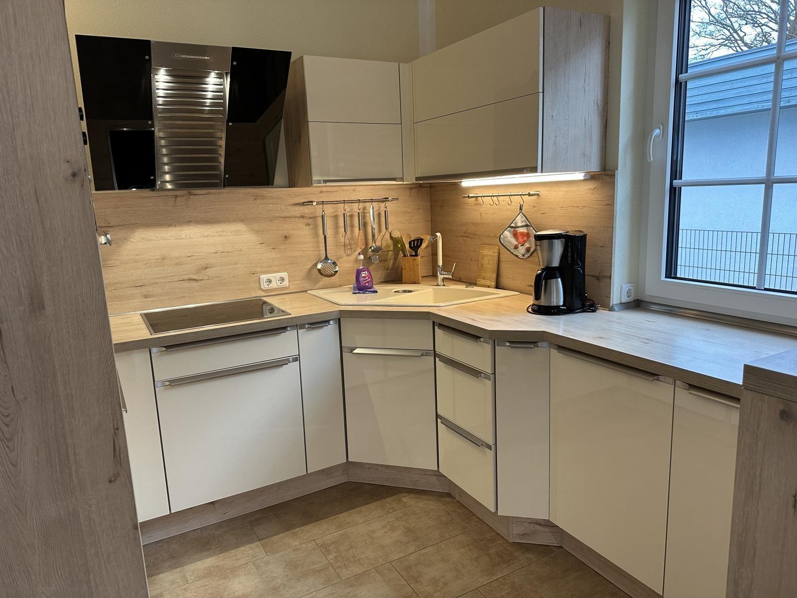 Küche mit Holzoptik, Spüle, Kaffeemaschine und Fenster.