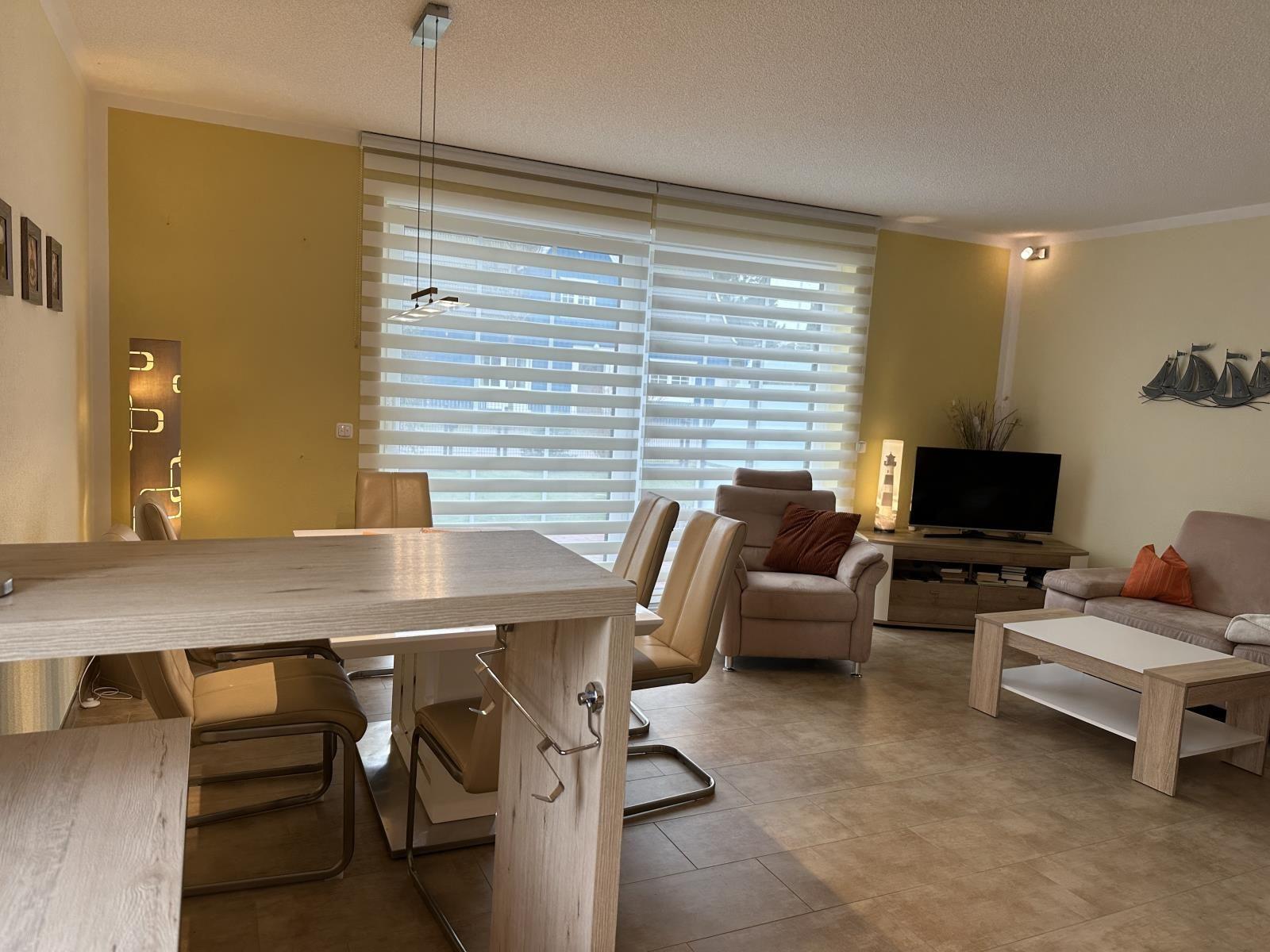 Wohn- und Essbereich mit Sofa, Fernseher und Essplatz.