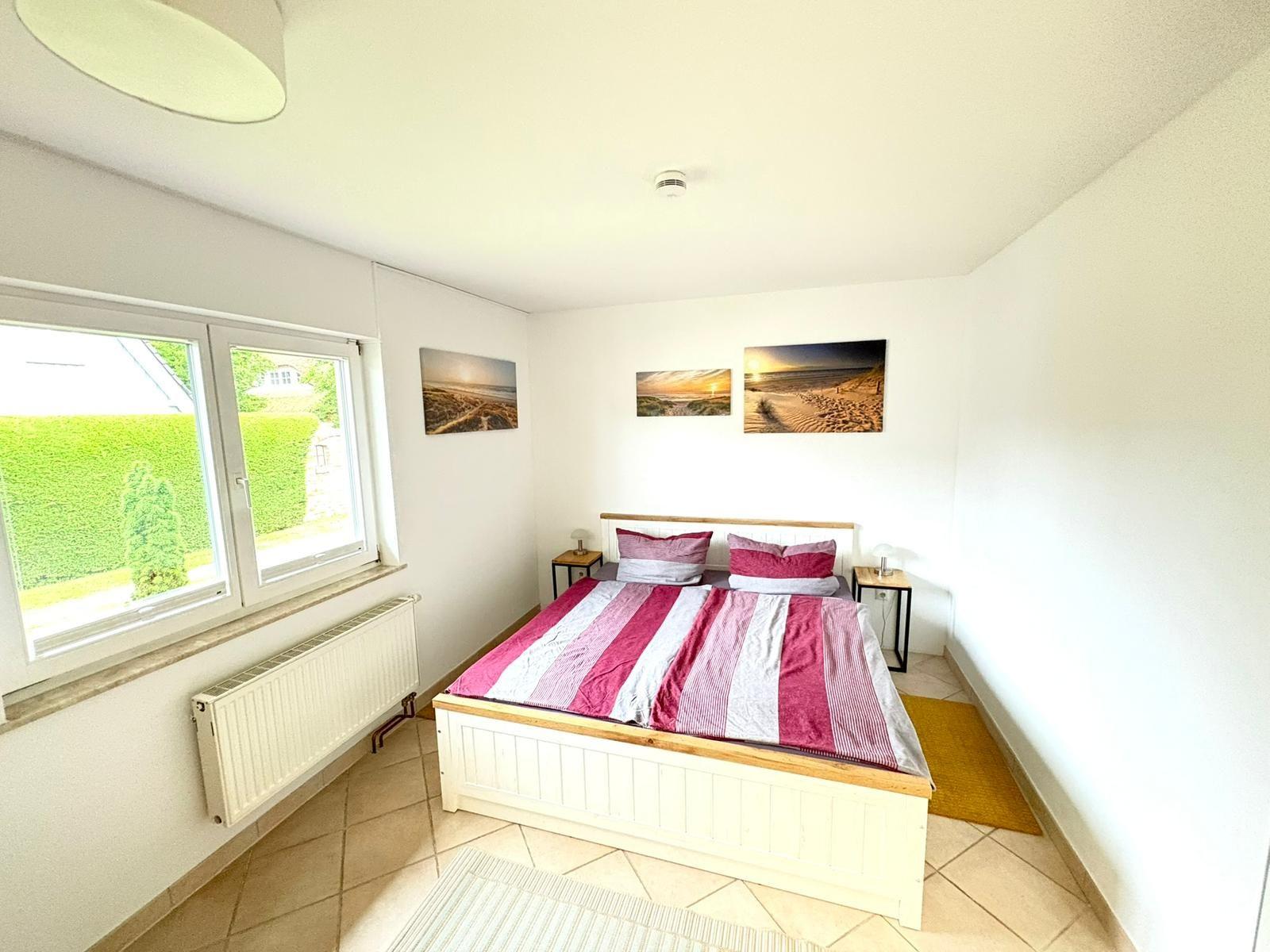 Schlafzimmer mit Bett, Fenster und Wandbildern