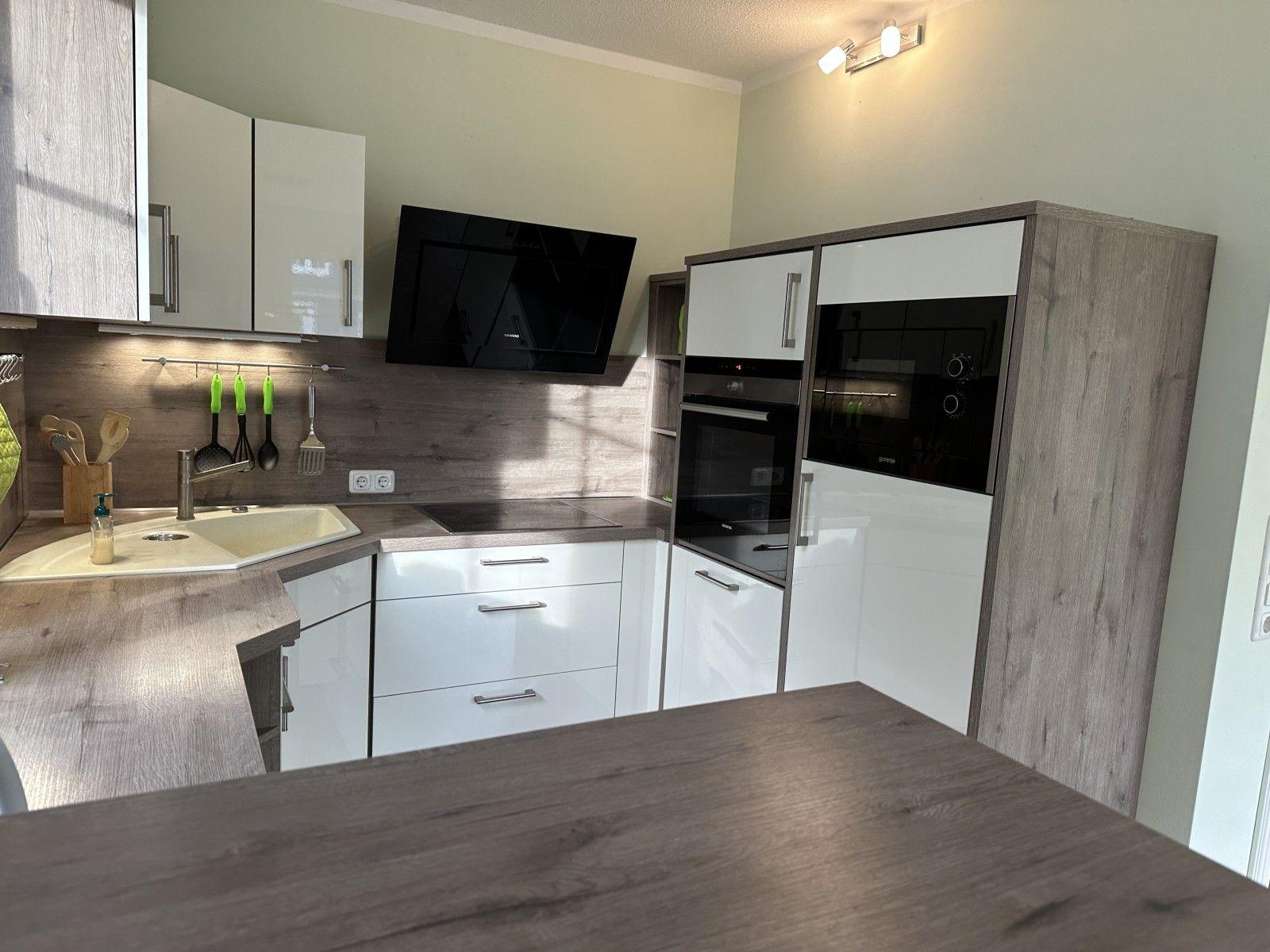 Moderne Küche mit Dunstabzug, Backofen und Arbeitsplatten.