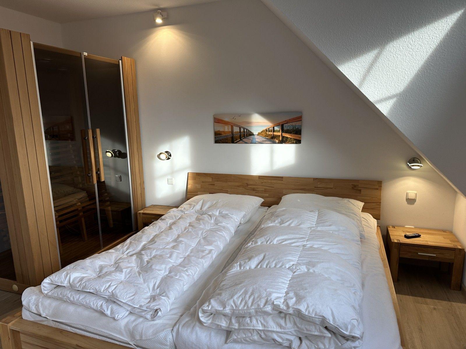 Schlafzimmer mit Doppelbett, Holzmöbel und Dachschräge.