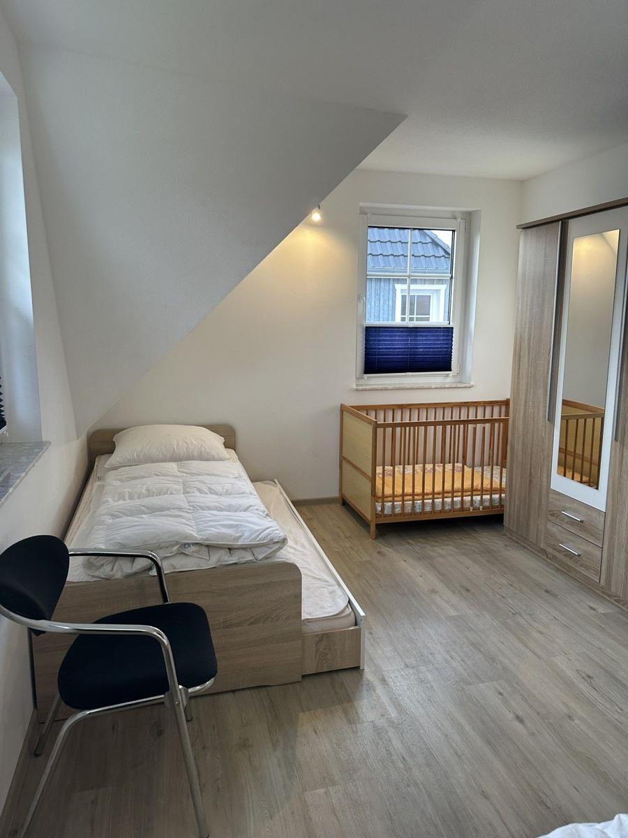 Schlafzimmer mit Einzelbett, Kinderbett und Kleiderschrank.