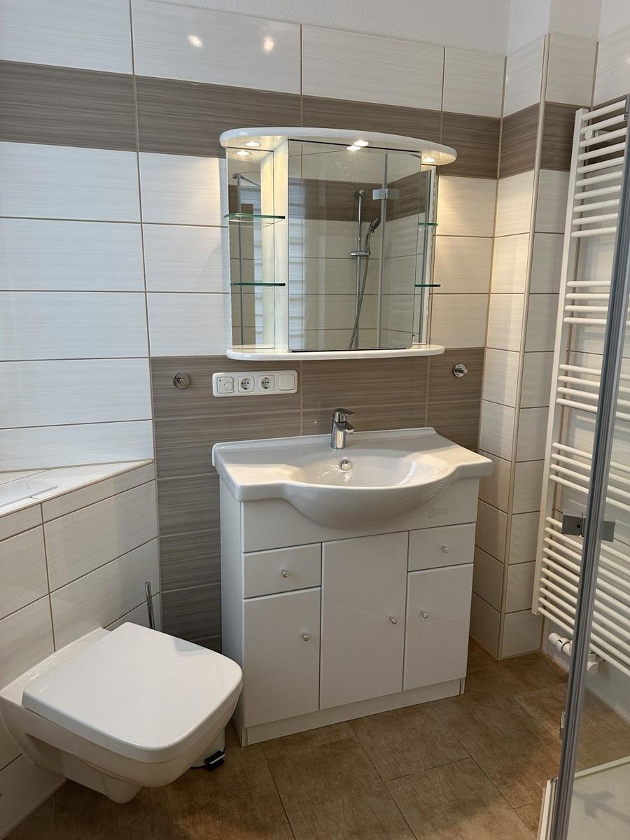 Badezimmer mit Waschbecken, Spiegel und Dusche