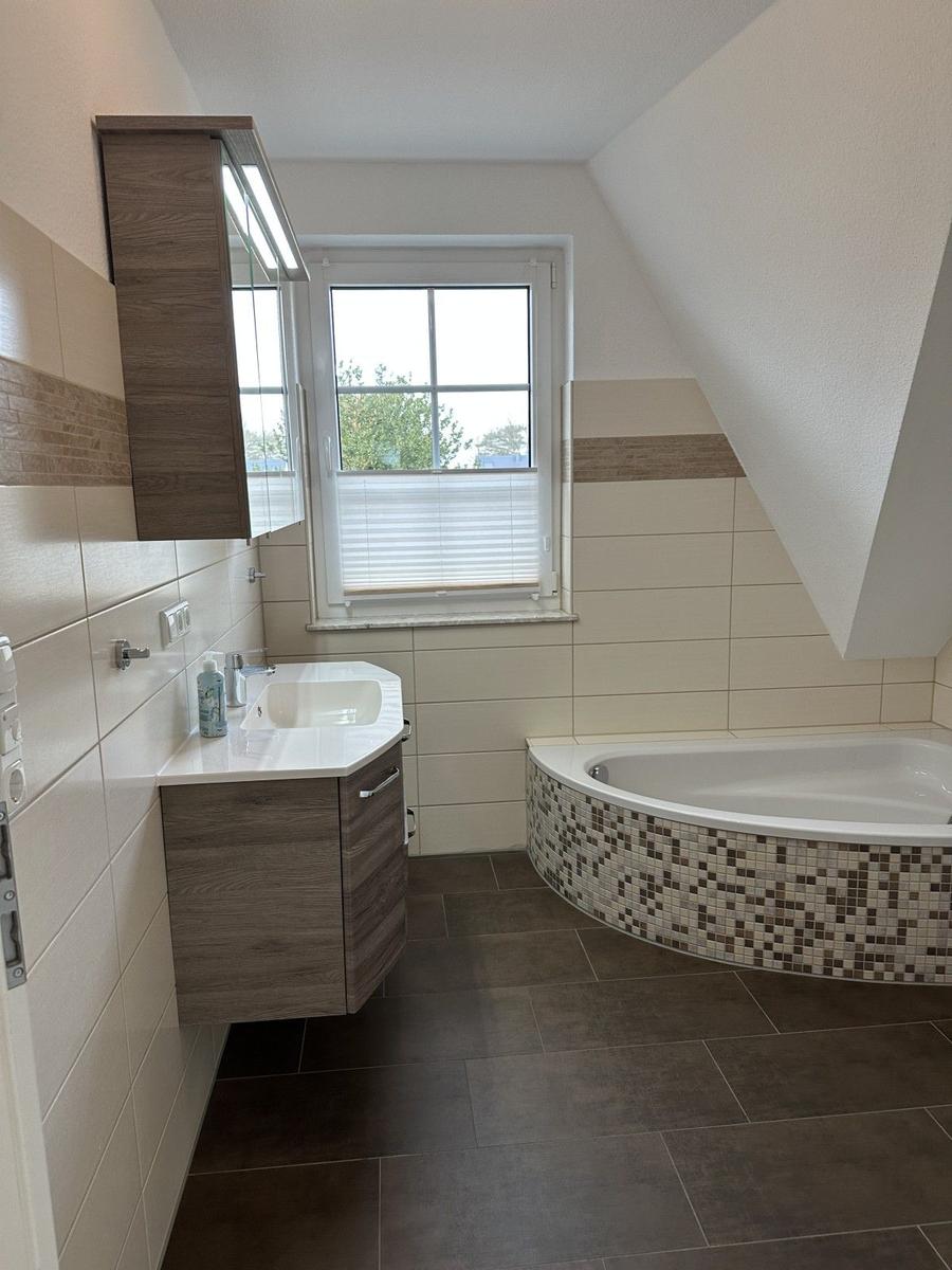 Badezimmer mit Badewanne, Waschbecken und Fenster