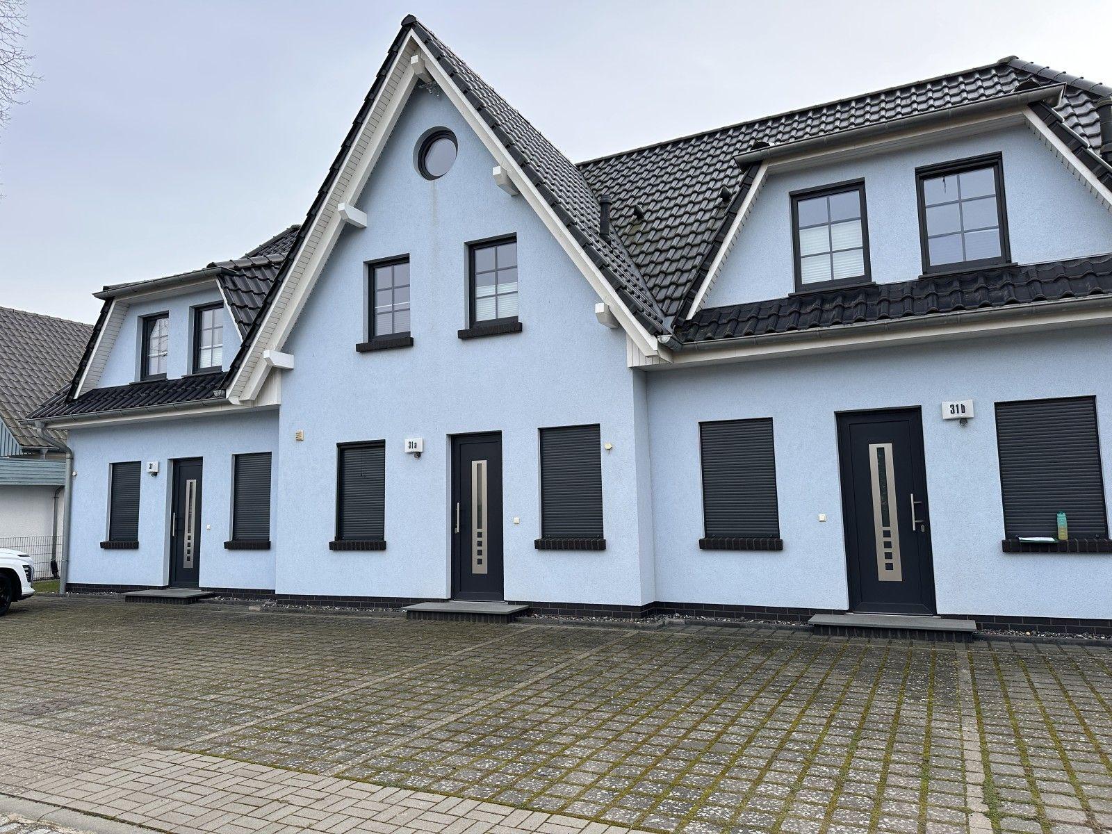 Ein hellblauer zweistöckiger Haus mit drei Eingängen und dunklen Fenstern.