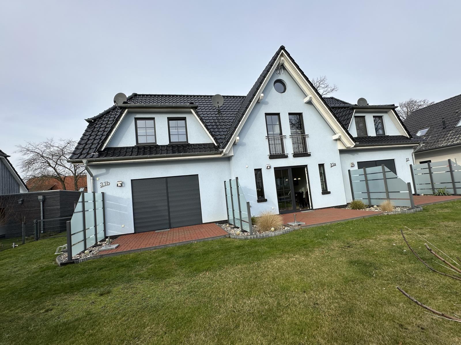 Moderne Villa mit Garage und Garten. Eingangstür und Fenster sichtbar.