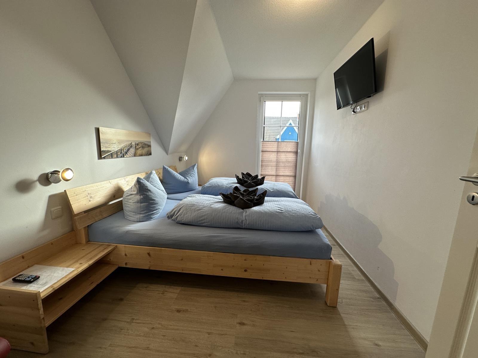 Schlafzimmer mit Doppelbett, Fernseher und Fenster