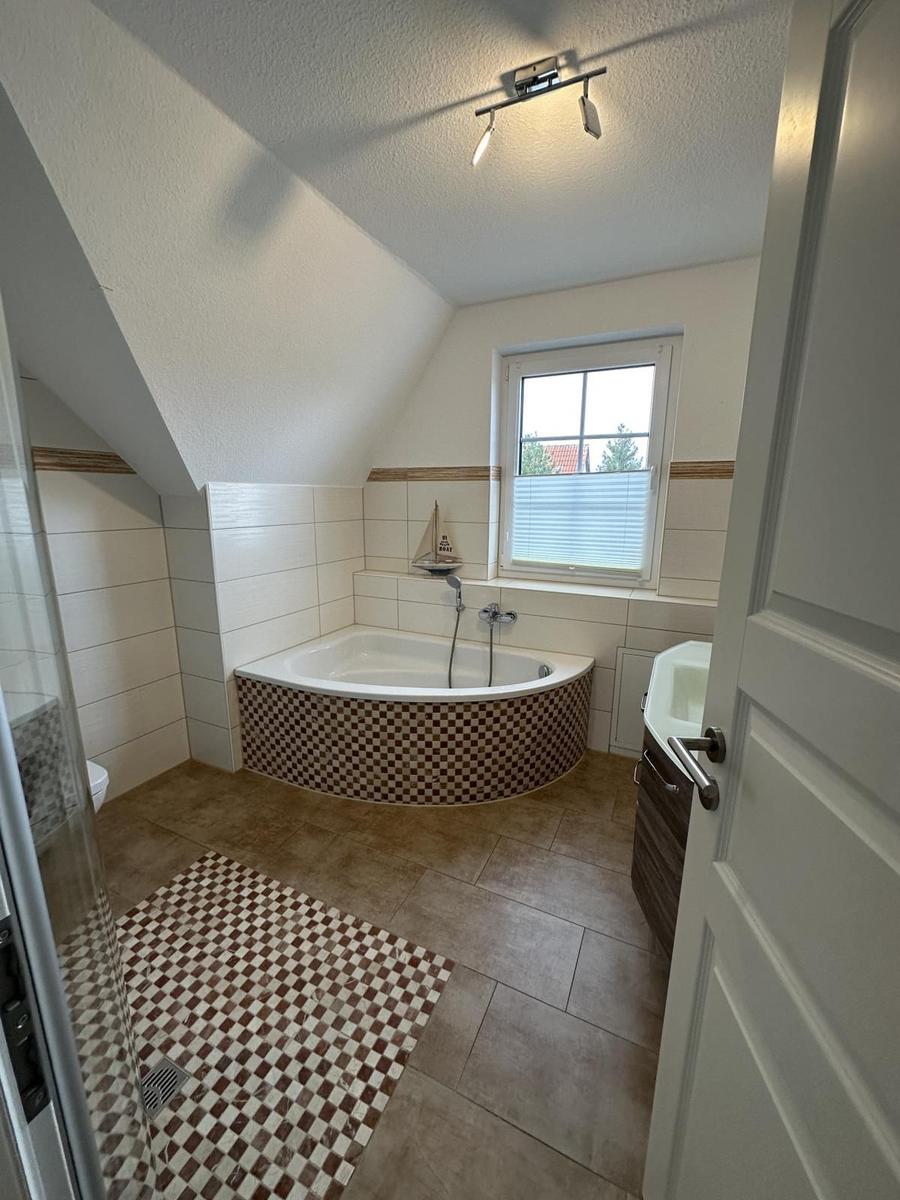 Badezimmer mit Badewanne, Dusche und Fenster