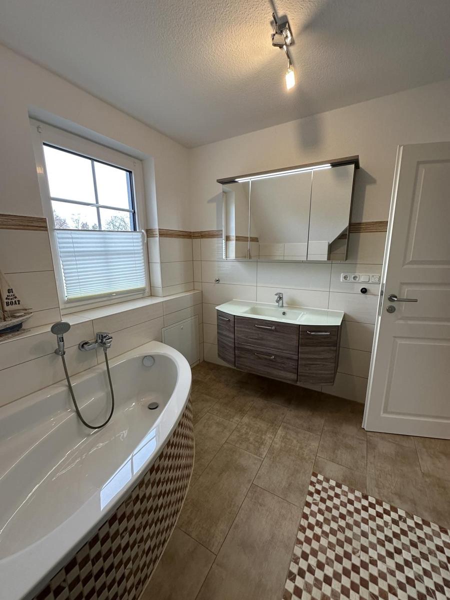 Badezimmer mit Badewanne, Waschbecken und Spiegel