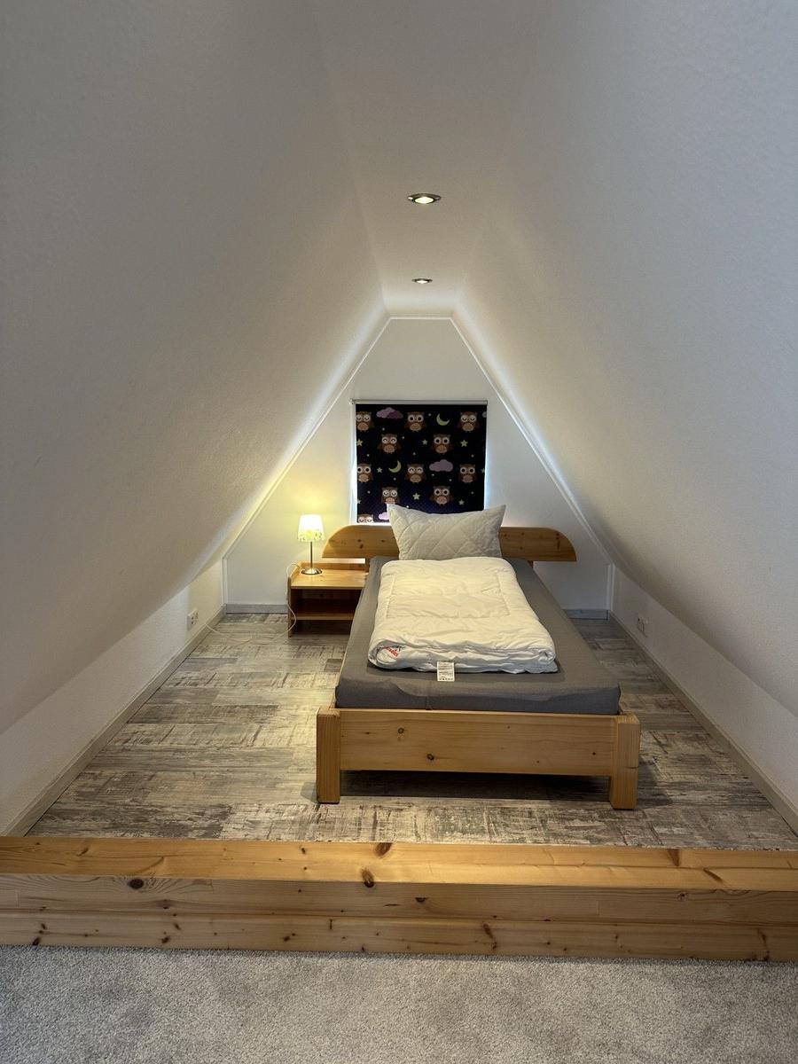 Schlafzimmer mit Dachschrägen, Bett und Nachttisch.