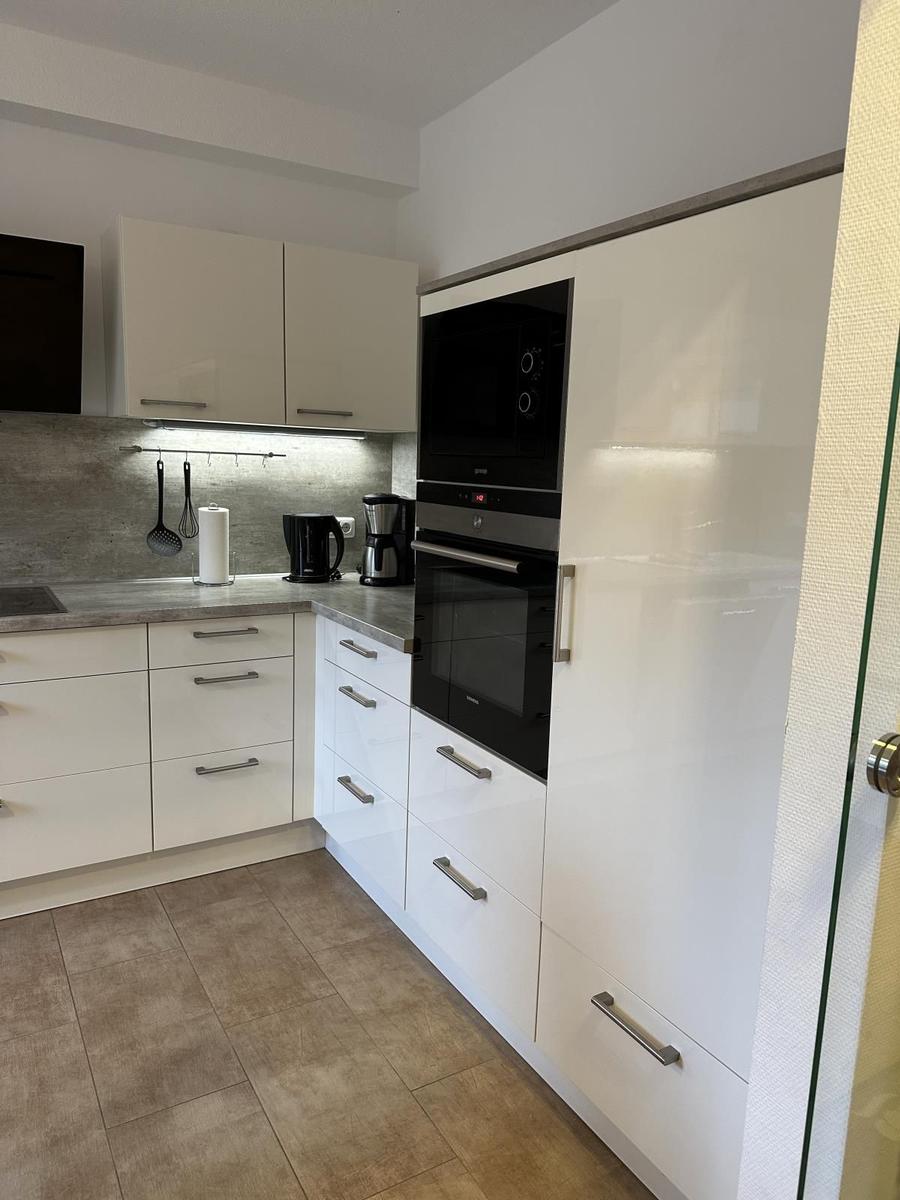 Moderne Küche mit weißen Schränken und integriertem Ofen.