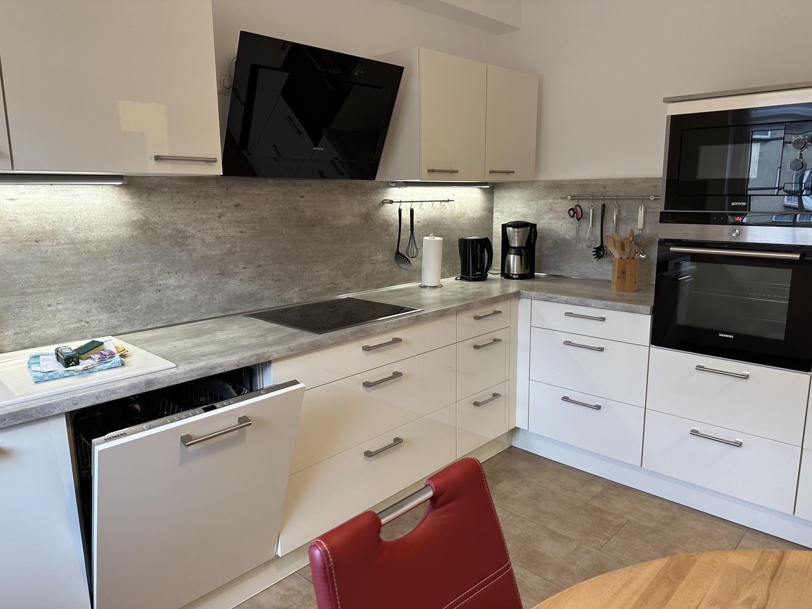 Moderne Küche mit weißen Schränken und Edelstahlgeräten.