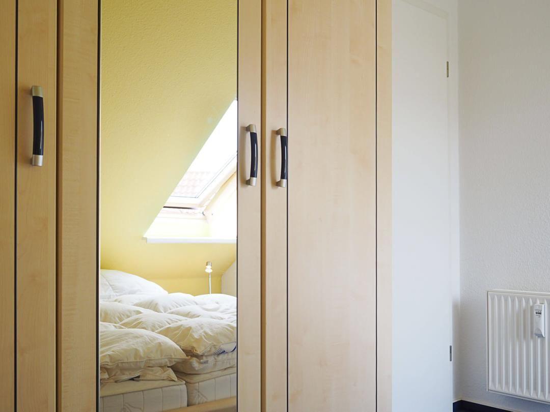 Schlafzimmer mit Dachschrägen und Dachfenster. Spiegelkabinett und Heizkörper sichtbar.