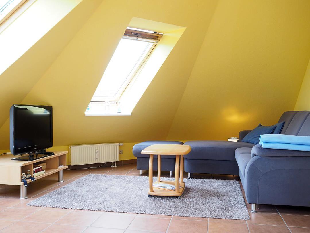 Wohnzimmer mit Sofa, Fernseher und Dachschrägenfenster.