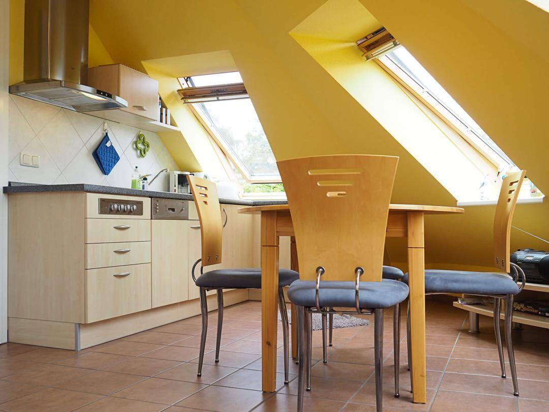 Küche mit Essbereich unter Dachschrägen mit Dachfenstern und Holzmöbeln.