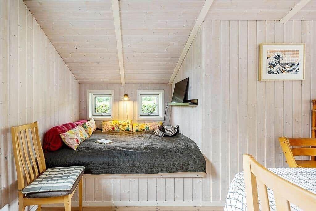 Bedroom with bed, windows, wall art, and TV.