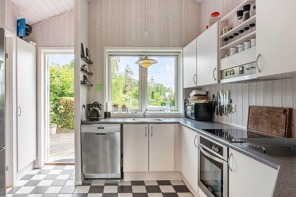 Kitchen with white cabinets, window and black-and-white floor