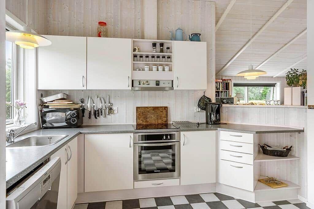 Kitchen with white cabinets, stainless steel appliances, and black-and-white floor tiles.