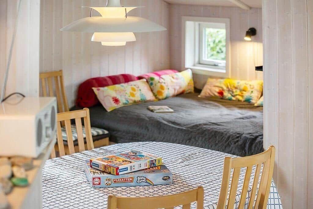 Bedroom with bed, window, and dining table with chairs.