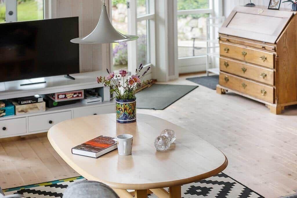 Living room with wooden floor, TV, coffee table, and flowers.
