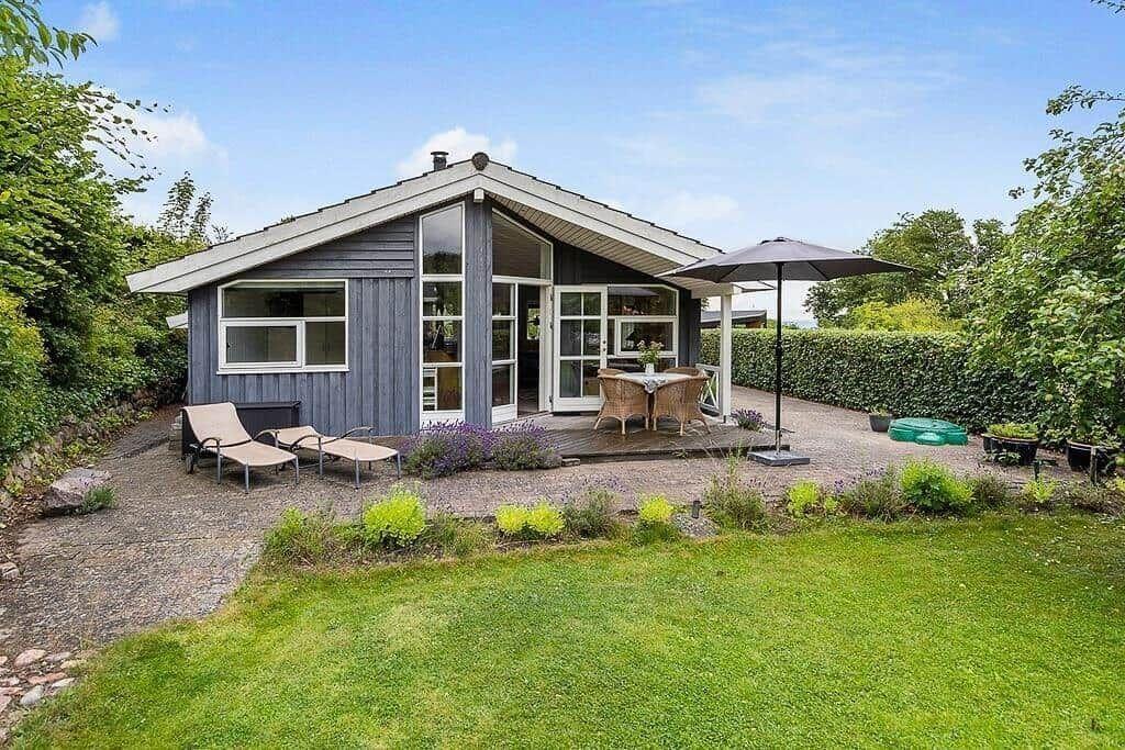 A gray house with a terrace, garden, and sun loungers.