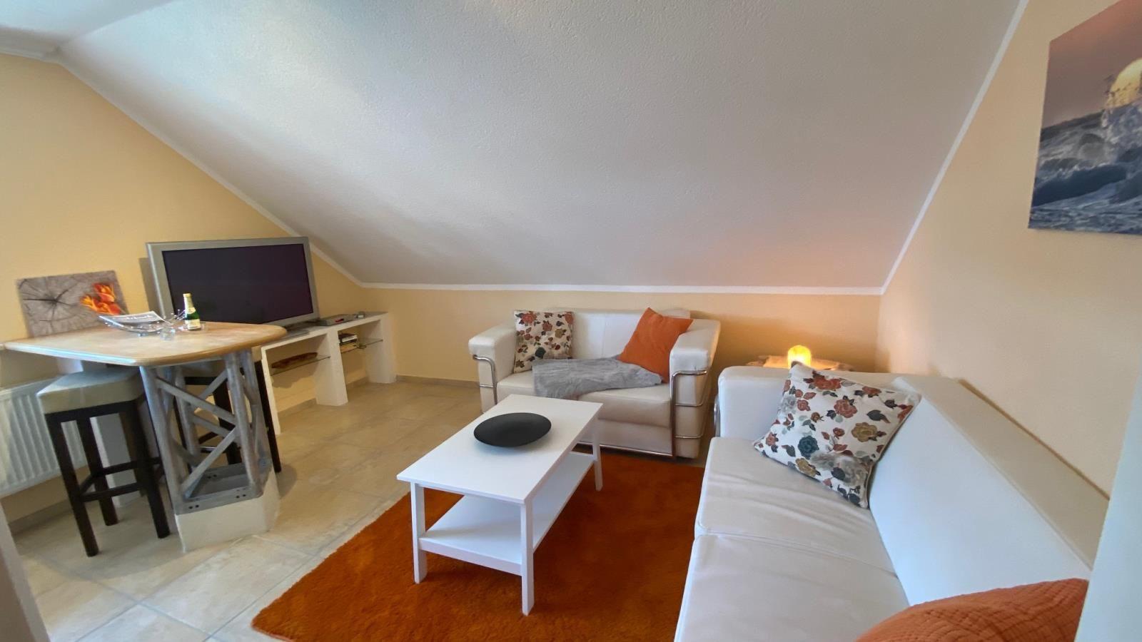 Wohnzimmer mit Sofa, Couchtisch und Fernseher unter Dachschräge