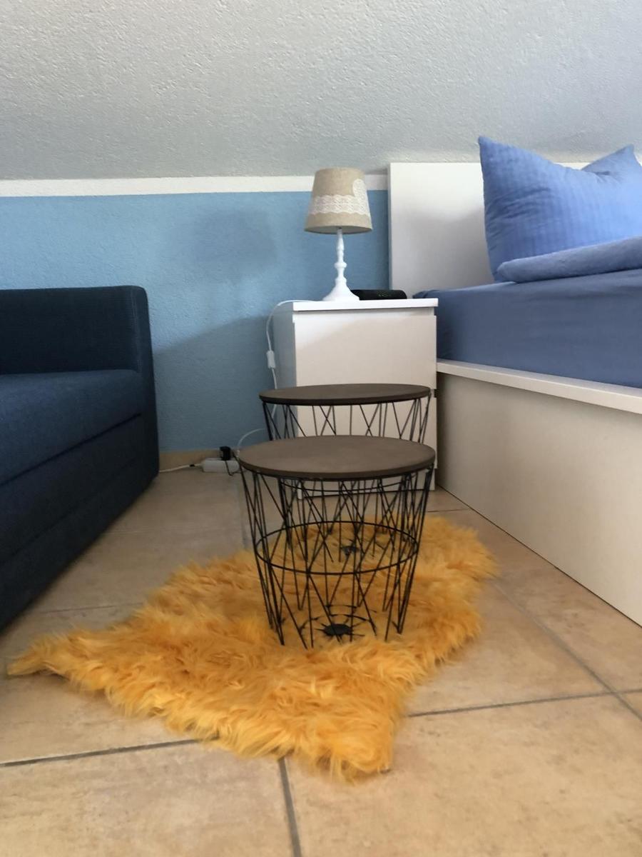 Schlafzimmer mit Bett, Sofa, Nachttisch und zwei Tischen auf Fellteppich.