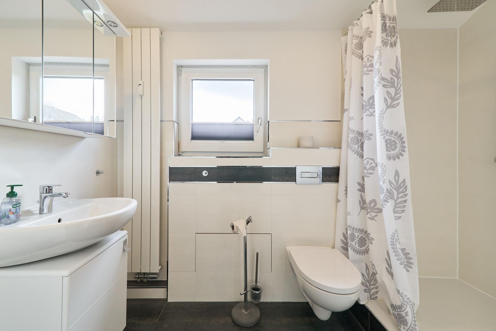 Badezimmer mit Waschbecken, Toilette und Duschvorhang