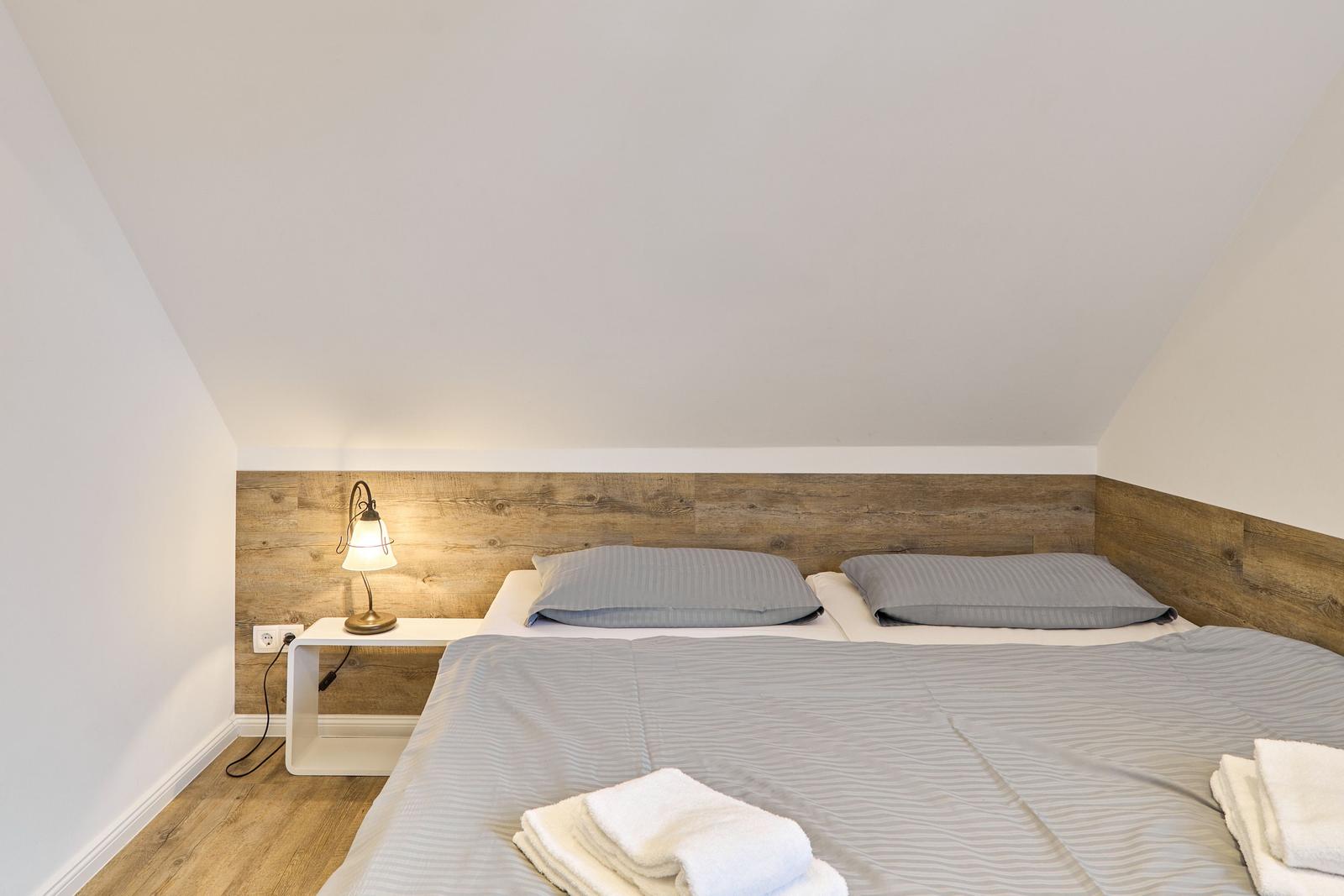 Schlafzimmer mit Doppelbett, Holzpaneelen und Nachttisch mit Lampe.