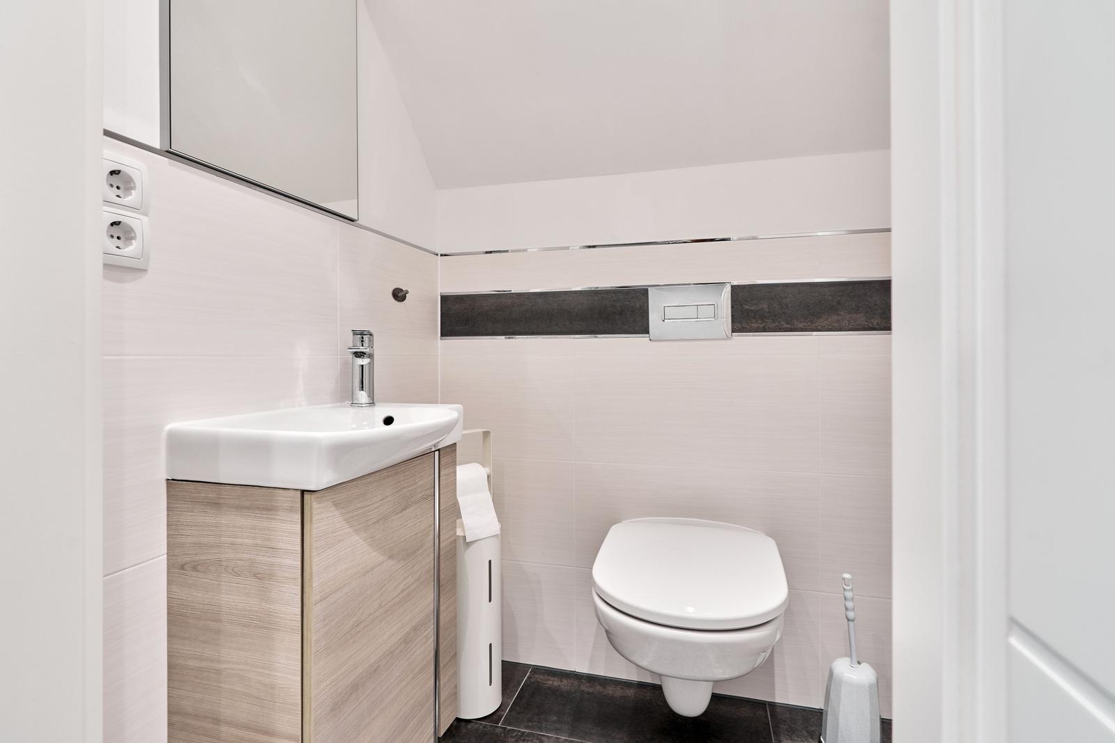 Badezimmer mit Waschbecken, Toilette und Spiegelschrank.