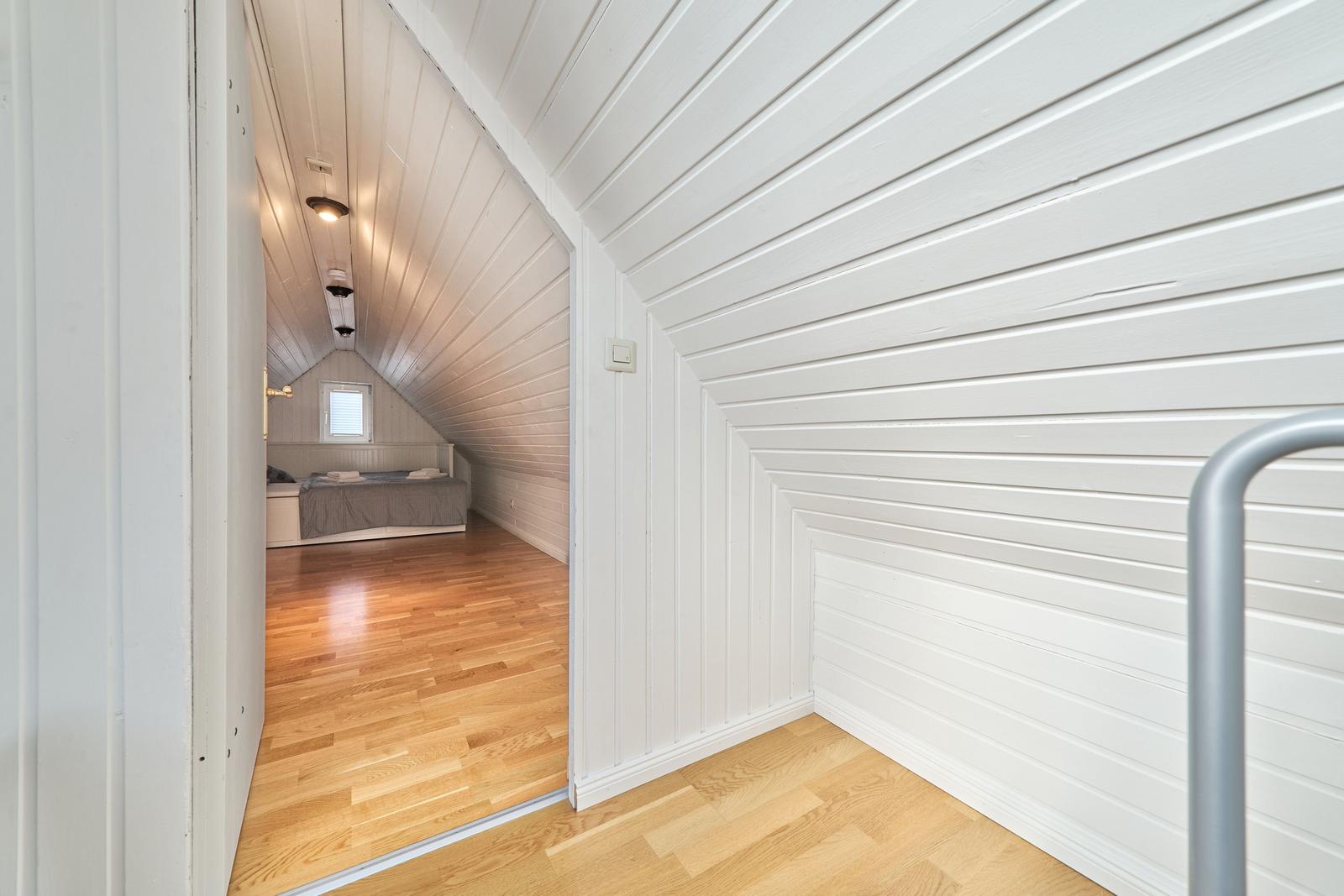 Schlafzimmer mit Dachschrägen, Holzboden und Bett unter Dach